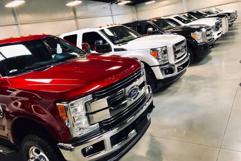 Row of used Ford Super Duty and other diesel pickups lined up in a showroom.